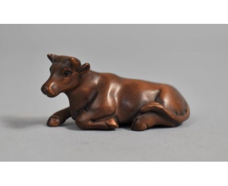 A Carved Wooden Netsuke in the form of a Recumbent Cow, Signed, 5cm Long 