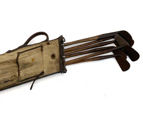 A vintage canvas and leather golf bag by Bryant, containing a quantity of antique golf clubs, hickory handled, to include Fra
