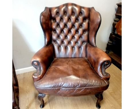 Brown leather button back wing armchair with removable feather filled seat cushion. In good used condition. 