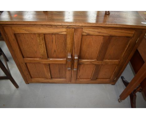 A reproduction oak panelled cupboard having shelf and drawer interior, approx. dimensions W110cm D 53cm H83cm