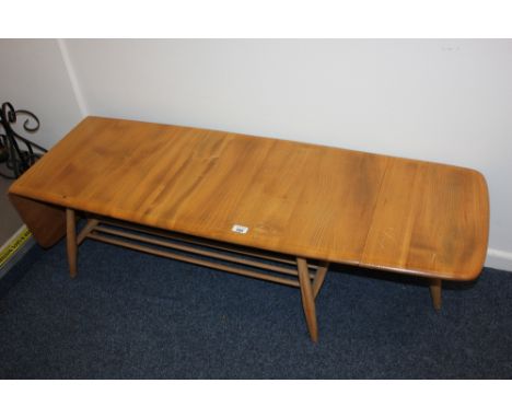 An Ercol pale wood drop flap coffee table, rounded rectangular top, with two end drop flaps, with extending swivel legs (one 