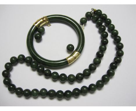 A hinged Jade Bangle with engraved mounts stamped 14K and a single row of Jade Beads