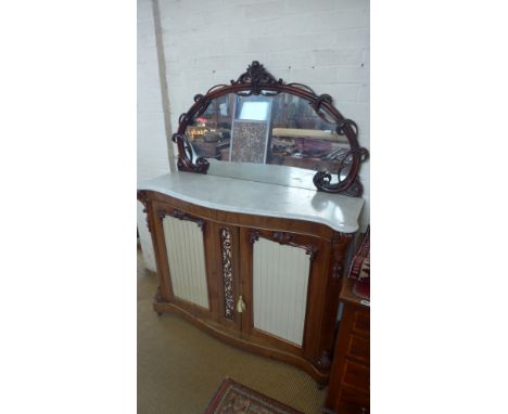 A late Victorian serpentine fronted marble topped credenza, the foliate carved mirror surround over marble above the central 