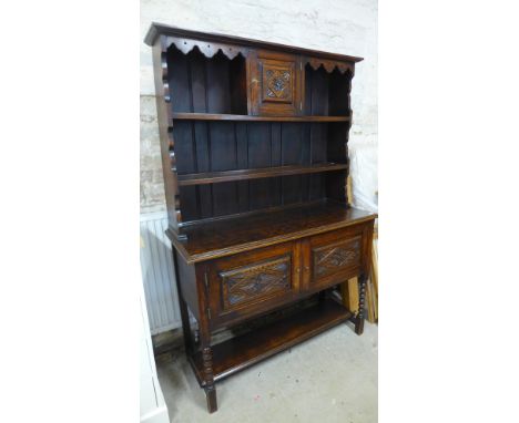 An early 20th century oak sideboard/dresser with plate rack over base of two doors raised on barley sugar twist supports, she