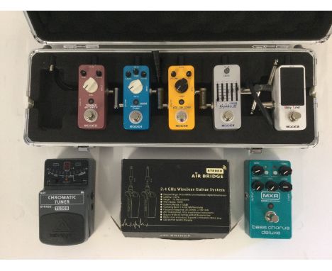 A collection of guitar pedals comprising an MXR bass chorus deluxe, various Mooer pedals, a Behringer tuner and a boxed Air B