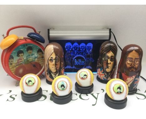Three John Lennon Russian dolls, a set of 4 Yellow Submarine baseballs, a Beatles neon light and an alarm clock.