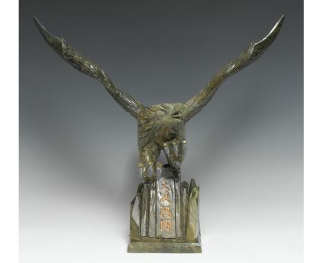 A Chinese green hardstone carving, of an eagle, the rocky base inscribed and picked out in gilt with calligraphy, 46cm high 