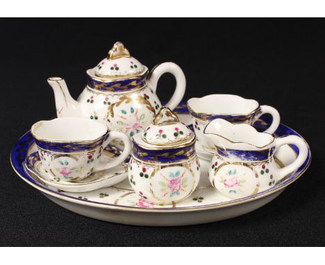 A Continental porcelain miniature tête-à-tête, comprising teapot, milk jug, sucrier, a pair of cups and saucers and an oval t