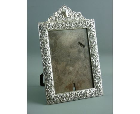 AN ELECTROPLATE EASEL PORTRAIT MIRROR, the wide frame decorated overall with flowers and scrolls to take a picture 18 x 12.5 