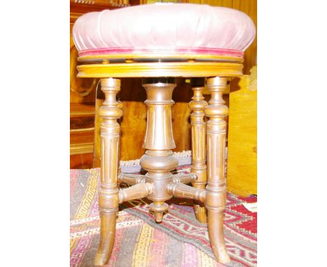 A WALNUT REVOLVING RISE & FALL PIANO STOOL stamped 'Brooks', having a button upholstered leather effect seat with a brass ris