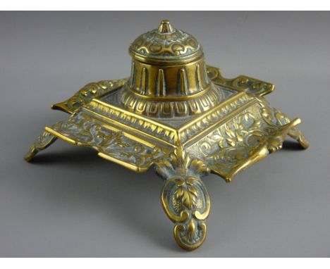 A DECORATIVE SQUARE BRASS INKSTAND with centre bowl and having white ceramic container (cracked)