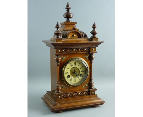 A CIRCA 1900 GERMAN OAK CASED MANTEL CLOCK, architecturally styled with finial caps and decorative brass mounts, on a stepped