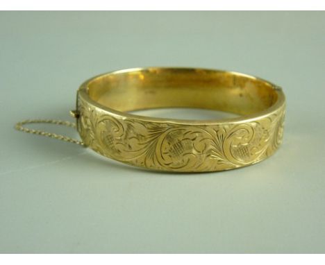 A NINE CARAT GOLD WIDE HOLLOW BANGLE with half bright cut decoration and safety chain, 20.7 grms (slight impact damage to bri