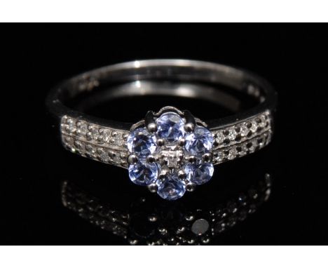 A new diamond and tanzanite flower head cluster ring, central diamond, surrounded by a band of six purple/blue round cut tanz