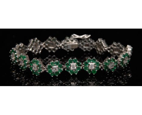 An emerald and white sapphire bracelet, sixteen flower heads, each with a central white sapphire surrounded by eight emeralds