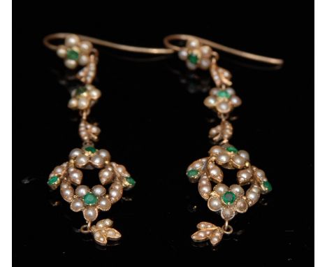 A pair of Edwardian seed pearl and emerald chandelier earrings, open flower head wreath drops, suspended from alternating lea