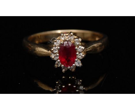 A ruby and diamond ring, central red ruby, surrounded by a band of twelve small round cut diamonds, 9ct gold shank, size O1/2