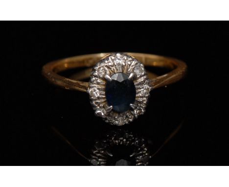 A sapphire and diamond ring ,central oval blue sapphire surrounded by eight illusion set diamonds, razor edge shoulders, plat