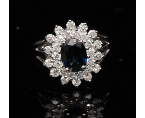 A new sapphire and diamond cluster ring, central oval deep blue sapphire, approx 1.32ct, surrounded by a twenty eight stone p