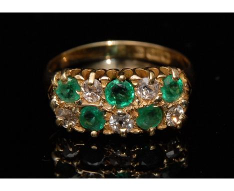 An emerald and diamond ring, the five pale green emeralds and five round brilliant cut diamond, set in an alternating double 