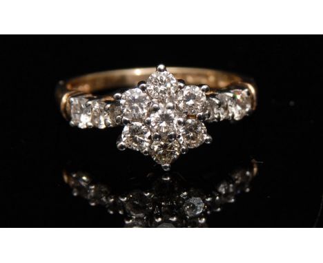 A seven stone diamond floral cluster ring, central raised round brilliant cut diamond, surrounded by six conforming diamonds,