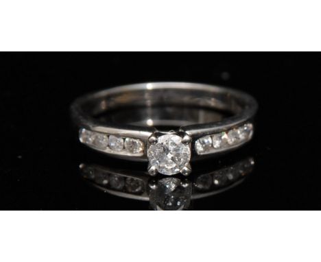 A new diamond ring, central round brilliant cut solitaire diamond, raised above flanking shoulders each set with four smaller