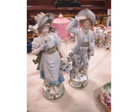 A PAIR OF BISQUE FIGURES modelled as a female and her companion each shown standing on a circular base 45cm high