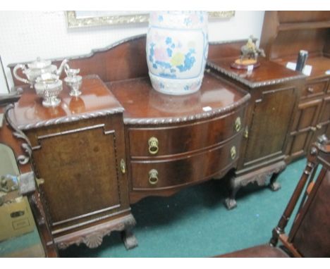 A CHIPPENDALE STYLE MAHOGANY SIDEBOARD of rectangular bowed outline with two frieze drawers and cupboards with brass lion mas