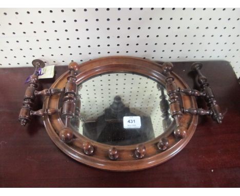 AN UNUSUAL VICTORIAN MAHOGANY FRAMED OVAL MIRROR with bobbin supports and pegs