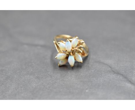 An opal and diamond chip ring having seven opal cabochons modelled as a stylised flower to claw set open mount on a 9ct gold 