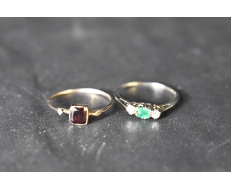 A small emerald and diamond trilogy ring having central baguette cut emerald on a thin white metal loop, all marks worn but p