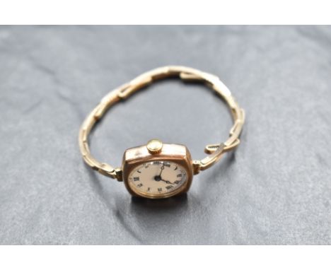 A lady's vintage 9ct rose gold wrist watch having Roman numeral dial to white face in a plain case on a stretch strap stamped