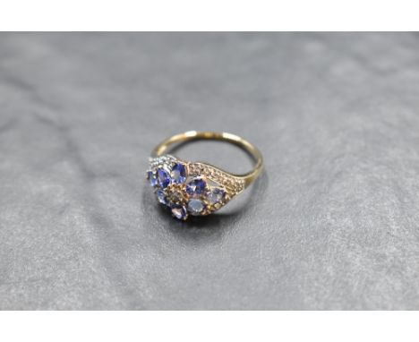 A tanzanite and diamond daisy cluster ring having a diamond chip oval border on a 14ct gold loop, size U &amp; approx 3.1g