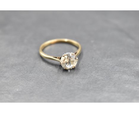 A solitaire ring bearing a clear stone, not a diamond in a raised claw set mount on a yellow metal loop stamped 9ct, plat, si