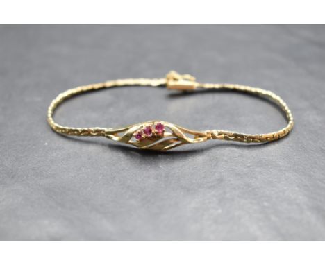 A 9ct gold bracelet having a central panel with three rubies in an open swirl mount on a fixed chain with box clasp, approx 5