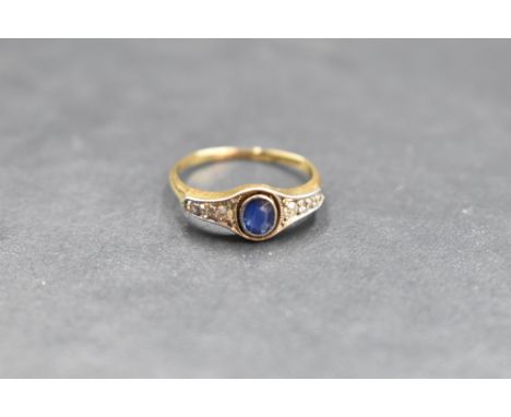 An early 20th century sapphire and diamond ring having a central oval sapphire flanked by six old cut diamonds in a miligrain