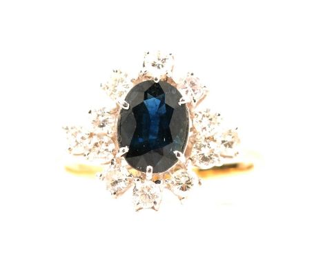 A sapphire and diamond cluster ring, the oval mixed cut sapphire, 8.8x6.5mm, claw set and surrounded by twelve individually c