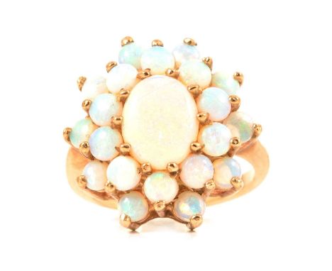 An opal cluster ring, the central oval cabochon cut opal surrounded by twenty round cabochon cut opals, all claw set in 9 car