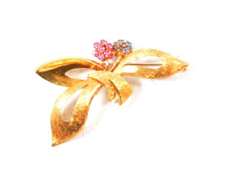 A sapphire and ruby brooch, an 18 carat yellow gold Florentine textured leaf spray, 50mm, set with two flower heads, one with