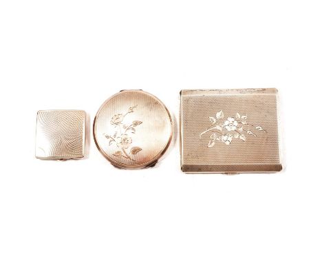 Two silver powder compacts and a cigarette case, a silver powder compact, engine turned design with engraved floral spray, 8c