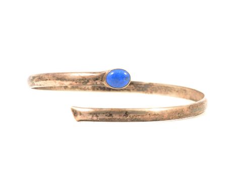 A silver upper arm bangle set with an oval cabochon cut lapis lazuli, 6mm wide half D shape, open ended with the lapis set to