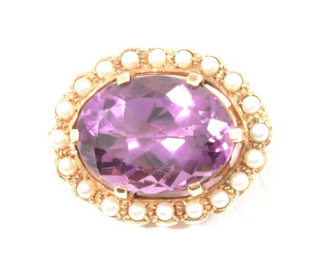 An amethyst and pearl brooch, the oval mixed cut amethyst, 24x18mm, six claw set in a yellow metal mount with a border of twe