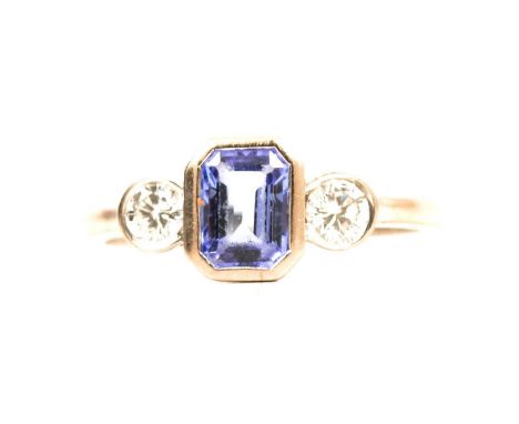 A tanzanite and diamond three stone ring, the emerald cut tanzanite, 6.5x5.5mm, collet set with a brilliant cut diamond to ea