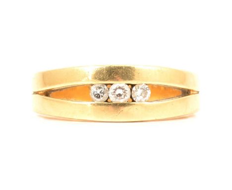 A diamond three stone ring, the three brilliant cut diamonds channel set to the centre of an open yellow metal mount size T, 