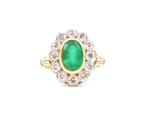 An emerald and diamond cluster ring, the oval mixed cut emerald, 9x6mm, collet set and surrounded by twelve brilliant cut dia