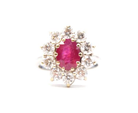 A ruby and diamond cluster ring, the oval mixed cut ruby, 8.5x7mm, claw set and surrounded by ten brilliant cut diamonds in a