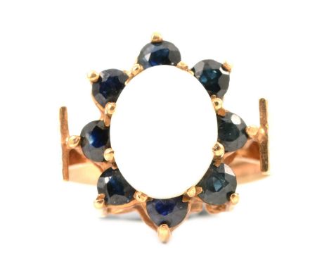 A 1970's opal and sapphire cluster ring, the oval cabochon cut opal, 10x8.5mm, claw set and surrounded by eight round sapphir