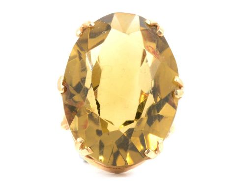 A 1960's large smoky quartz dress ring, the oval mixed cut stone, having a slightly yellow hue, 25x18mm, double claw set in a