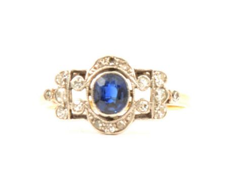 A diamond and blue stone cluster ring in the Art Deco style, the oval blue sapphire coloured stone millegrain set with eighte