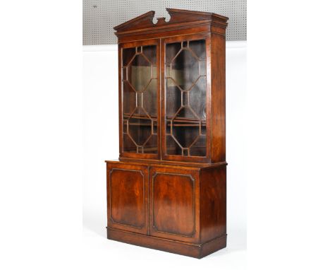 A George III style mahogany bookcase, with broken pediment and dentil cornice the glazed doors with octagonal astragals, encl